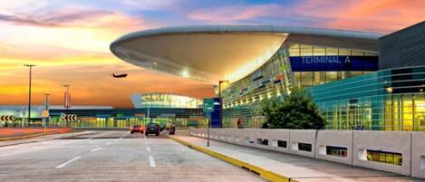Una terminal aeroportuaria moderna con techo curvo, fachada de vidrio y cielo despejado.