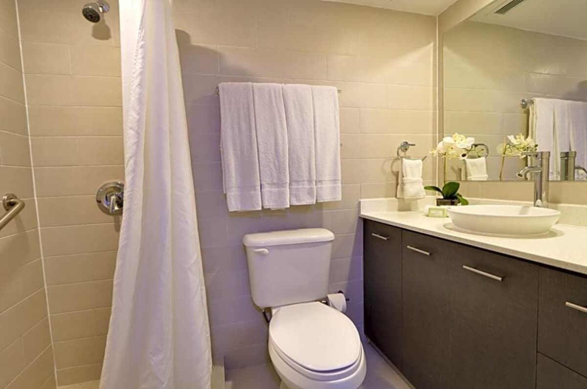 Un baño con inodoro, lavamanos, espejo y cortina de ducha.