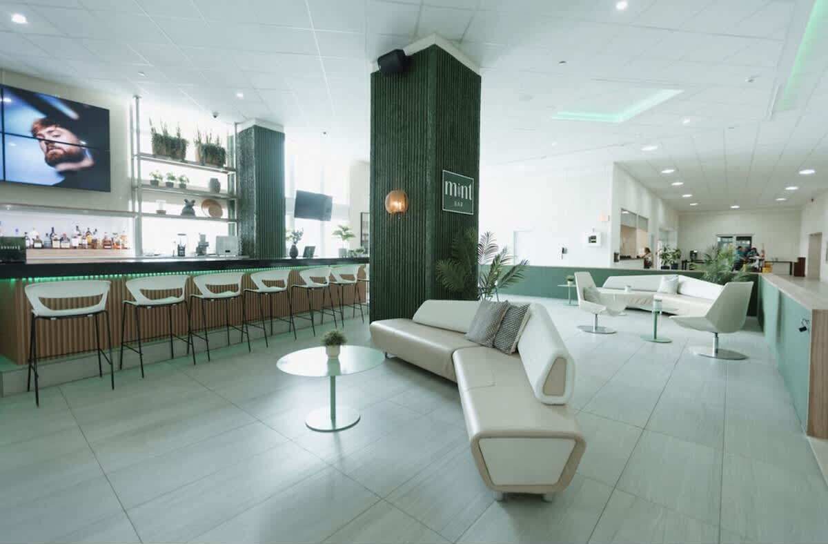 Un hall d’hôtel moderne doté d’un bar, de coins salon et d’un grand écran.
