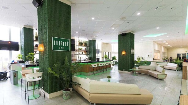 Eine moderne Hotelhalle mit Barbereich, Sitzgelegenheiten und einer Rezeption.