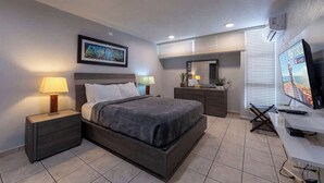 Una moderna camera d'hotel con un letto, comodini, una scrivania, una TV e una finestra con persiane.