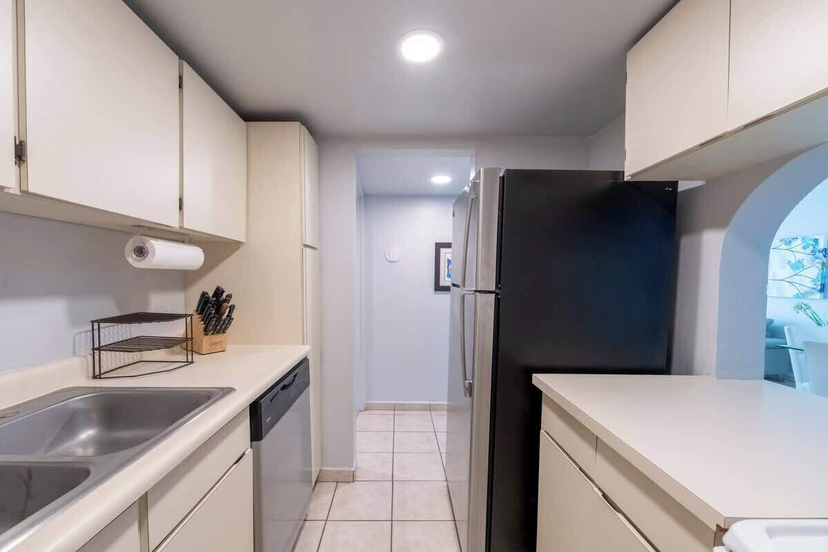 A compact kitchen with a sink, countertop, and a refrigerator.