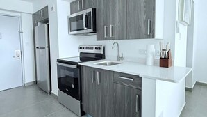 Una cocina moderna con gabinetes grises, electrodomésticos de acero inoxidable y una encimera blanca.