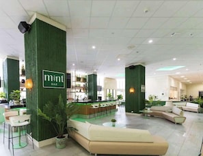 Eine moderne Bar mit grünen Akzentwänden, einer Rezeption und Sitzgelegenheiten.