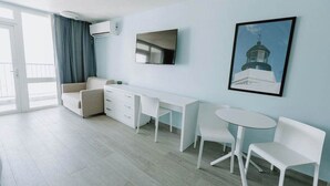 Une chambre moderne avec un canapé, un bureau, une télévision et un tableau au mur.