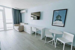 Ein modernes Zimmer mit einer Couch, einem Schreibtisch, einem Fernseher und einem Gemälde an der Wand.