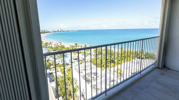 Un balcon avec vue sur une plage et l’océan.