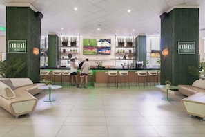Eine Bar mit Theke, Sitzgelegenheiten und Zierpflanzen.