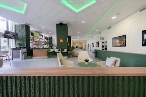 Eine moderne Hotelhalle mit Empfangstresen, Sitzgelegenheiten und Kunstwerken an den Wänden.