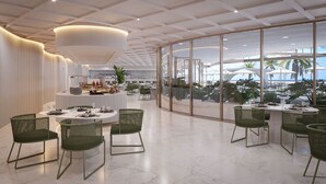 A modern dining area with round tables, green chairs, and a view of the beach through large windows. - Oikos Maragogi Resort - GAV Resorts (Maragogi)