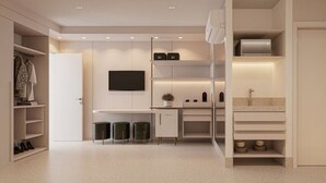 A modern, minimalist kitchen with built-in appliances, a flat-screen TV, and a walk-in closet with shelves and a hanging rod. - Oikos Maragogi Resort - GAV Resorts (Maragogi)
