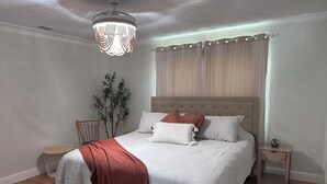 Una camera da letto con un letto, un comodino, una lampada, una pianta e un lampadario.