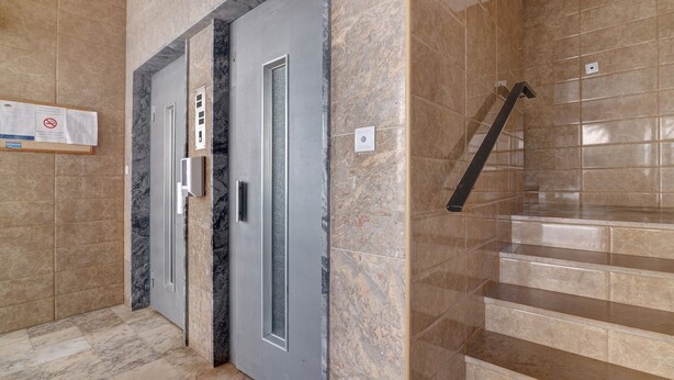 A hallway with a marble floor, a grey door with a glass panel, and a staircase with beige tiles. - Apartment 'Lili' with Wi-Fi (Armação de Pêra)