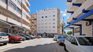 A multi-story building with balconies, parked cars, and a clear sky. - Apartment 'Lili' with Wi-Fi (Armação de Pêra)