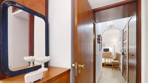 A wooden dresser with a mirror, a small white box, and a door leading to a hallway with a wooden chair and a table. - Apartment 'Lili' with Wi-Fi (Armação de Pêra)