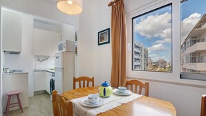 A compact kitchen with a microwave, a washing machine, and a dining area with a table set for two. - Apartment 'Lili' with Wi-Fi (Armação de Pêra)
