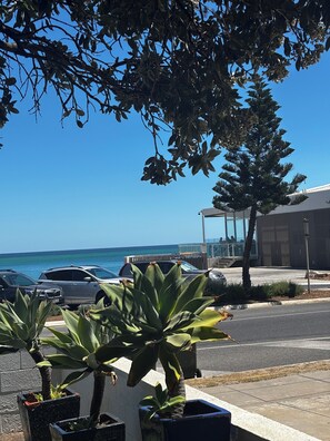 A parking area with potted plants, a clear blue sky, and a view of the ocean. - *Beachfront Escape in West Beach! Ocean views, steps from the sand! (West Beach)