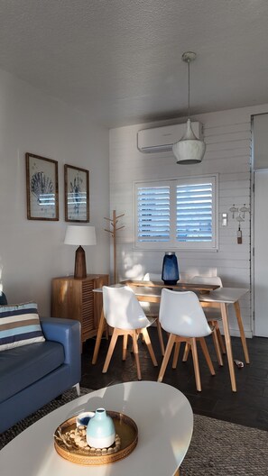 A modern living room with a sofa, dining table, chairs, and a coffee table. - *Beachfront Escape in West Beach! Ocean views, steps from the sand! (West Beach)