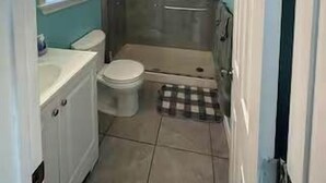 Un baño pequeño con inodoro, lavamanos y cabina de ducha.
