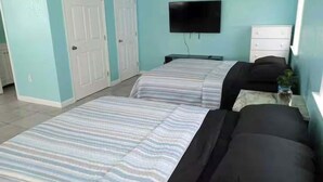 Un dormitorio con dos camas, televisión, cómoda y ventilador de techo.