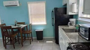 Una cocina equipada con refrigerador, estufa, microondas y una mesa de comedor con sillas.