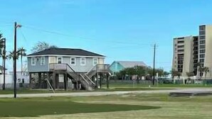 Un barrio residencial con una casa, una escalera y un campo cubierto de césped.