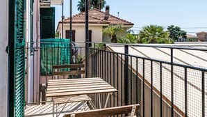 Un balcon avec une balustrade en métal, un banc en bois et un portail vert.
