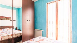 Une chambre à coucher avec un lit, une armoire, un radiateur et une fenêtre avec des rideaux.