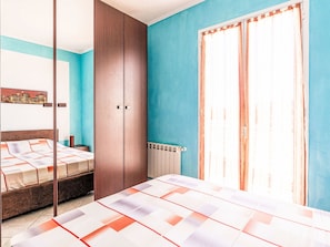 Una camera da letto con un letto, un armadio, un termosifone e una finestra con tende.