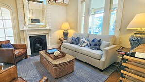 A living room with a fireplace, a sofa, a chair, a coffee table, and a lamp.
