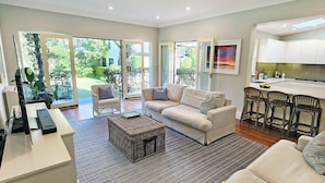 A modern living room with a sofa, coffee table, and a kitchen area with bar stools.