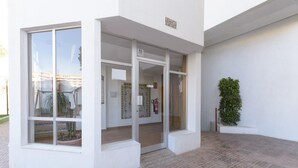 A building entrance with glass doors, a fire extinguisher, and a potted plant. - CASA DO BRASIL - Cozy apartment with shared pool and free Wi-Fi (Gandia)