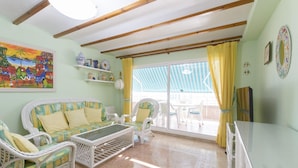 A room with a sofa set, a coffee table, a TV, and a balcony with yellow curtains. - CASA DO BRASIL - Cozy apartment with shared pool and free Wi-Fi (Gandia)
