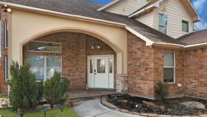 A brick house with a front porch, a white door, and a small garden with shrubs. - Charming 3-bedroom house with private pool in Houston (Houston)