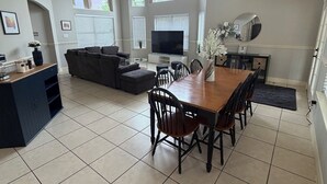 A spacious living area with a dining table, chairs, a sofa, a TV, and a ceiling fan. - Charming 3-bedroom house with private pool in Houston (Houston)