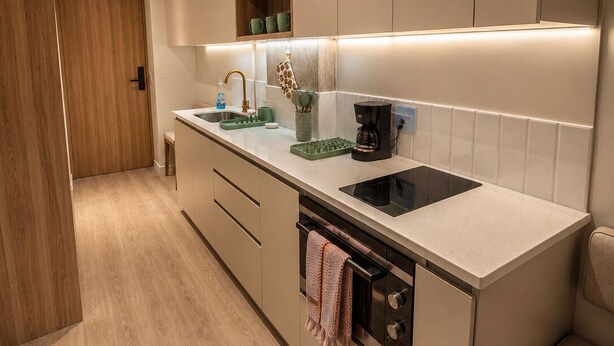 Una cucina moderna con mobili in legno, forno a incasso, lavello e un piano di lavoro con una macchina per il caffè.