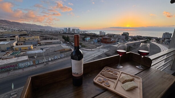 A balcony with a bottle of wine, glasses, and a tray of cookies.