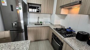 A modern kitchen with a stainless steel refrigerator, a built-in oven, a gas stove, and a sink.