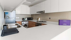 Una cocina moderna con electrodomésticos de acero inoxidable, lavadora integrada y una isla pequeña.