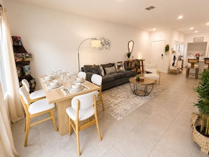 Una sala moderna con comedor, sofá, mesa de centro y estantería.