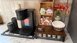 A Keurig coffee maker on a kitchen counter, a wooden shelf with coffee pods, a vase with flowers, and a ceramic bowl. - Stunning Pool House Between Lakewood and Mountain (Mountain)