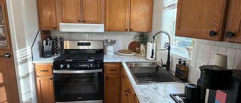 A kitchen with wooden cabinets, a stainless steel stove, a sink, and a coffee maker.