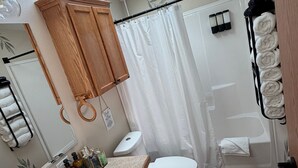 A bathroom with a skylight, a sink, a toilet, a shower curtain, and a towel rack. - Stunning Pool House Between Lakewood and Mountain (Mountain)
