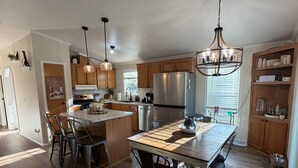 A modern kitchen with wooden cabinets, a stainless steel refrigerator, and a dining area with a round rug. - Stunning Pool House Between Lakewood and Mountain (Mountain)