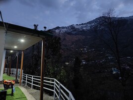 A balcony with a view of a snow-covered mountain and a valley.