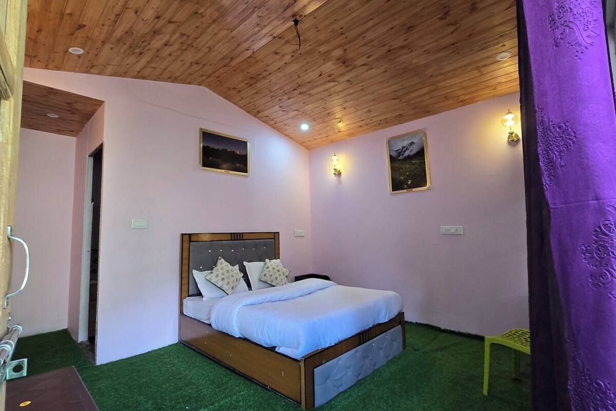 Un dormitorio con techo de madera, una cama con cabecera, dos luces fijadas a la pared y una pequeña foto en la pared.