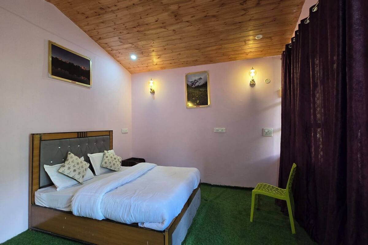 Un dormitorio con techo de madera, una cama con ropa de cama blanca, dos lámparas de pared y una silla.