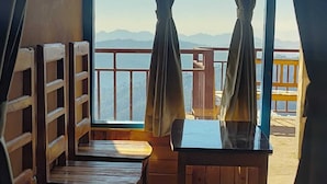 Ein Zimmer mit einer hölzernen Sitzbank, einem Tisch und Blick auf Berge durch große Fenster.