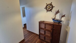 A hallway with wooden flooring, a wall-mounted ship's wheel, and a model ship on a cabinet. - 2 rooms appartement, A/C, piscine, tennis (ST MANDRIER SUR MER)