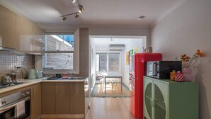 Een moderne keuken met een eethoek, een rode koelkast en een groene kast.